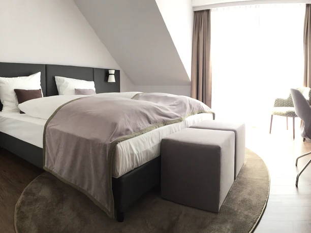 Doppelzimmer Helles, gemütliches Hotelzimmer mit Doppelbett, modernem Schreibtisch, Stuhl und großen Fenstern.