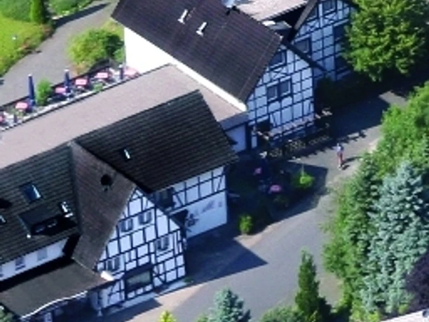Außenansicht Luftaufnahme eines traditionellen Fachwerkhauses mit umliegender grüner Landschaft und Terrasse.