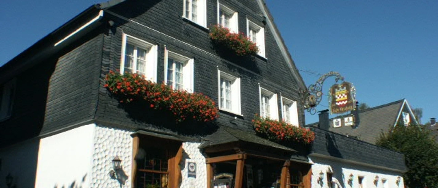 Hotel Feste Neustadt Traditionelles, schwarzes Fachwerkhaus mit weißen Wänden, blumengeschmückten Fenstern und Gasthausschild.