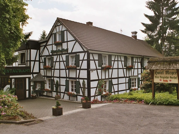 Aussenansicht Historisches Fachwerkhaus mit Blumenkästen, daneben ein Schild "Hotel Meyer, eine Bergische Gaststätte".