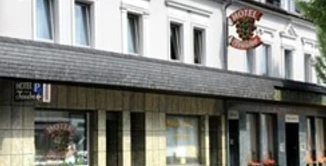 Zimmerbeispiel Historisches Hotelgebäude mit weißer Fassade, sieben Fenstern und einem Eingang mit Hotelschild.