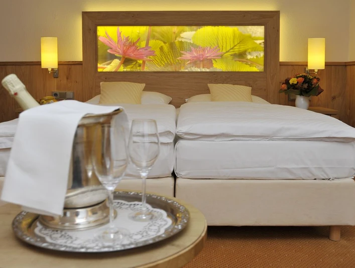 Gronauer Tannenhof Zwei Einzelbetten in einem Hotelzimmer, dekoriert mit gelben Kissen, Blumenbild an der Wand.