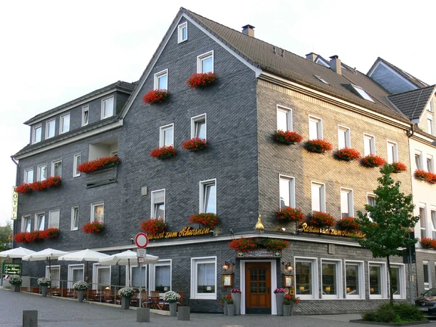 Zum Schwanen Ein traditionelles, mehrstöckiges Hotel schmückt sich mit blumengeschmückten Fenstern und Außenterrasse.