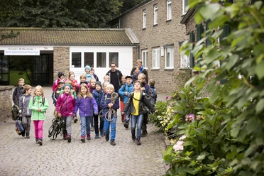 Jugendherberge Wipperfürth Eine Gruppe fröhlicher Schulkinder auf einem gepflasterten Hof vor einem Backsteingebäude.