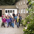 Jugendherberge Wipperfürth Eine Gruppe fröhlicher Schulkinder auf einem gepflasterten Hof vor einem Backsteingebäude.