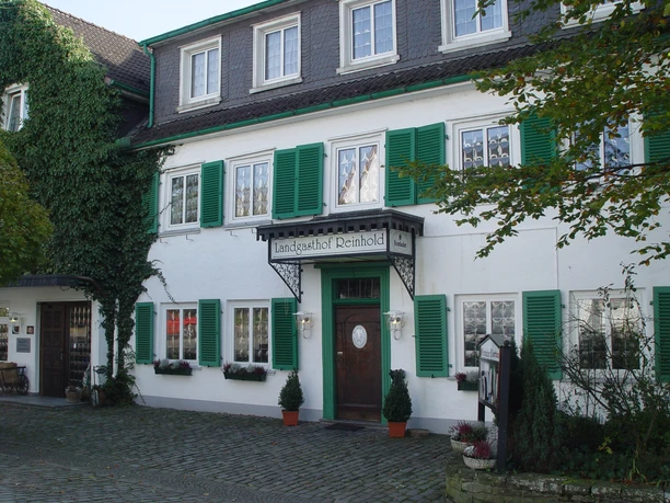 Aussenansicht Historisches Gasthaus mit grünen Fensterläden, weißen Blumenkästen und einem einladenden Eingang.