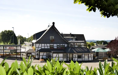 Landhotel Napoleon Fachwerkhaus im Grünen, eingebettet in eine ländliche Umgebung bei klarem Himmel und Sonnenschein.