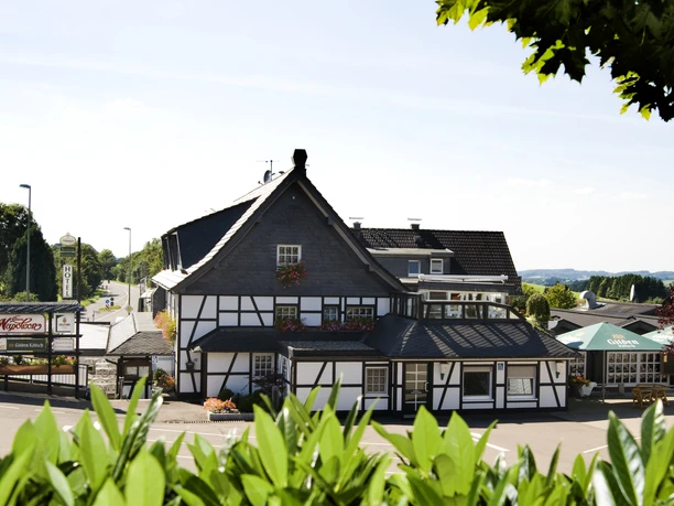 Landhotel Napoleon Fachwerkhaus im Grünen, eingebettet in eine ländliche Umgebung bei klarem Himmel und Sonnenschein.