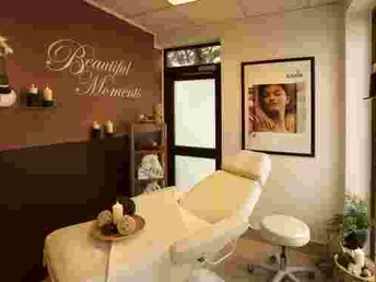 Beauty Anwendungsraum Ein gemütlicher, stilvoll eingerichteter Kosmetiksalon mit Behandlungsliege, Kerzen und Pflanzen.