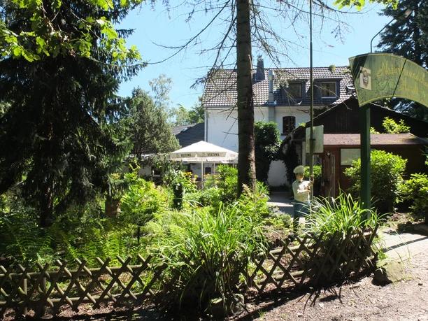 Haus Hardt Gemütlicher Garten eines Gasthofs mit Sonnenschirmen, umgeben von üppigem Grün und einem Holzzaun.