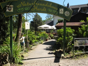 Haus Hardt Eingangsbereich des Naturfreundehauses Hardt mit grüner Bogenbeschriftung und einladender Terrasse.