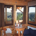 Zimmer Rustikaler Holztisch in gemütlichem Raum mit Panoramablick auf grüne, bewaldete Hügel im Hintergrund.