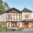 Waldhotel Mangold Traditionelles Fachwerkhotel in idyllischer Umgebung, umgeben von grünen Bäumen und Natur.