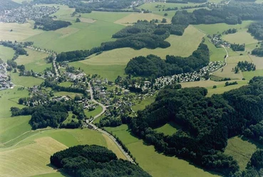Luftbild Luftbild zeigt eine ländliche Siedlung umgeben von Feldern und Wäldern, Sommeridylle sichtbar.