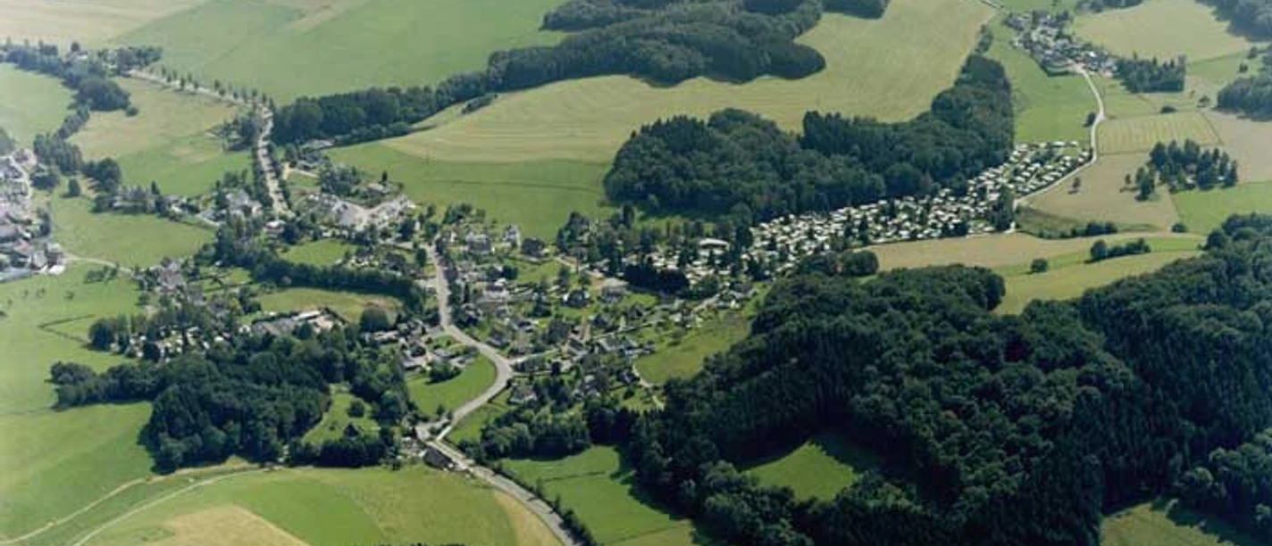 Luftbild Luftbild zeigt eine ländliche Siedlung umgeben von Feldern und Wäldern, Sommeridylle sichtbar.