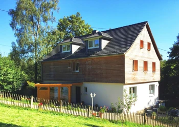 Pension Konradshof Großes, modernes Holzhaus mit Giebeldach in ländlicher Umgebung, umgeben von Bäumen und einem Garten.