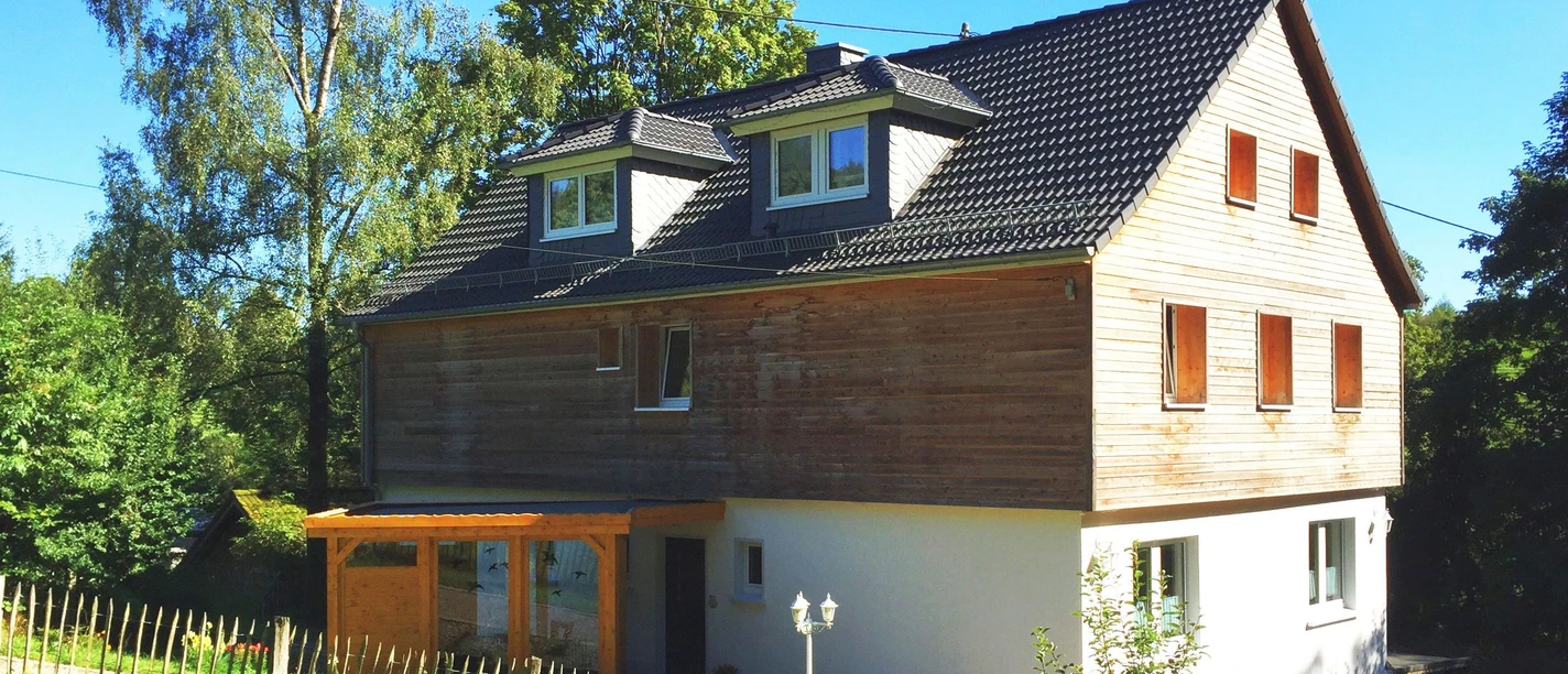 Pension Konradshof Großes, modernes Holzhaus mit Giebeldach in ländlicher Umgebung, umgeben von Bäumen und einem Garten.