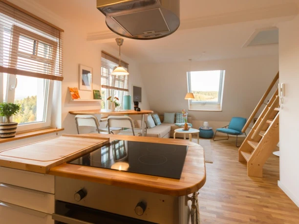 Villa Ruth - Wohnung 5 Wohnzimmer Helle Dachgeschosswohnung mit offener Küche, Holzfußboden, Esstisch und Sofa, viel Tageslicht.