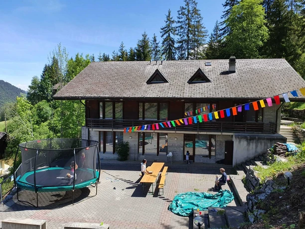 Vue extérieure de la maison de vacances Edelweiss Maison de groupe en bois vue de l'extérieur, devant laquelle est accroché un drapeau tibétain