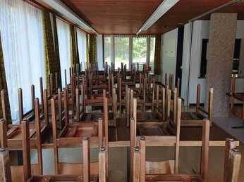 La grande salle à manger de la maison de groupe Essraum mit Tischen und hochgestellten dunkelbraunen StühlenDining room with tables and high dark brown chairsSalle à manger avec tables et chaises marron foncé placées en hauteur