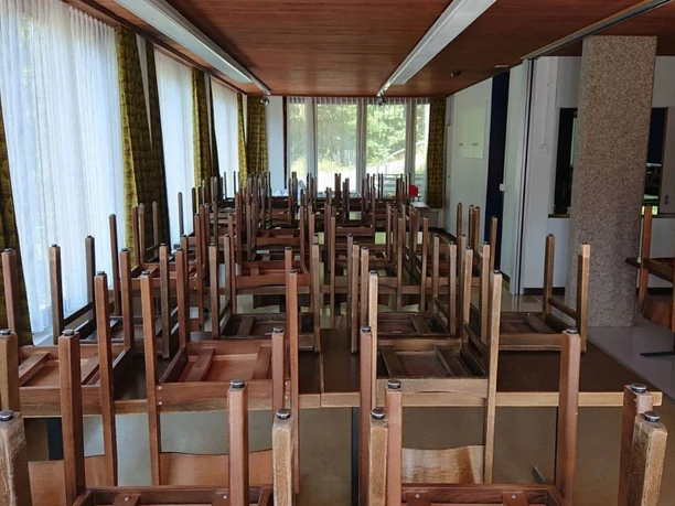La grande salle à manger de la maison de groupe Salle à manger avec tables et chaises marron foncé placées en hauteur