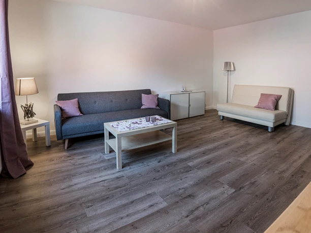 Wohnzimmer Wohnzimmer mit grauem Sofa, weißer Schlafcouch, Couchtisch und dunklem Holzfußboden.