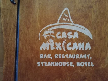 Casa Mexicana Logo aus Holz mit einem Sombrero, Bar, Restaurant, Steakhouse und Hotelangebot.Casa Mexicana logo made of wood with a sombrero, bar, restaurant, steakhouse and hotel offer.Casa Mexicana-logo lavet af træ med en sombrero, bar, restaurant, steakhouse og hoteltilbud.Casa Mexicana logo van hout met een sombrero, bar, restaurant, steakhouse en hotelaanbod.