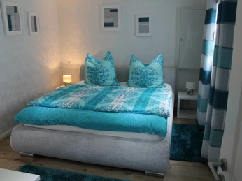 Ferienhaus Leon: Ein Schlafzimmer mit Doppelbett in Blautönen und stilvollen Dekorationselementen.Vacation home Leon: A bedroom with a double bed in blue tones and stylish decorative elements.Feriebolig Leon: Et soveværelse med dobbeltseng i blå toner og stilfulde dekorative elementer.Vakantiehuis Leon: Een slaapkamer met een tweepersoonsbed in blauwe tinten en stijlvolle decoratieve elementen.