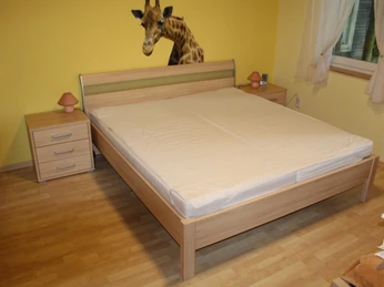 Ferienwohnung Reuter Ein schlichtes Doppelbett aus Holz mit zwei Nachttischen, vor einer gelben Wand mit Giraffenmotiv.
