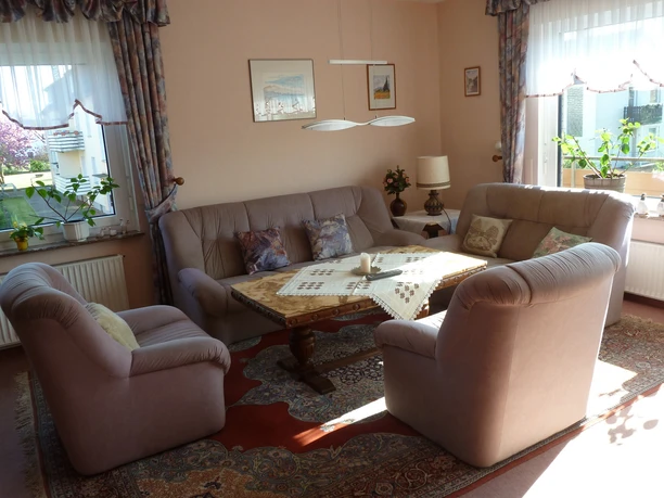Bright living room with comfortable seating area, carpeted floor and decorations on a wooden table.