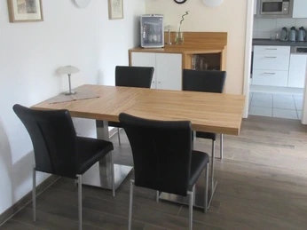 Hotel Ambiente Nienburg Moderner Essbereich mit Holz-Esstisch und vier schwarzen Stühlen, harmonisch kombiniert mit Küche.Modern dining area with wooden dining table and four black chairs, harmoniously combined with the kitchen.Moderne spiseplads med spisebord i træ og fire sorte stole, harmonisk kombineret med køkkenet.Moderne eethoek met houten eettafel en vier zwarte stoelen, harmonieus gecombineerd met de keuken.