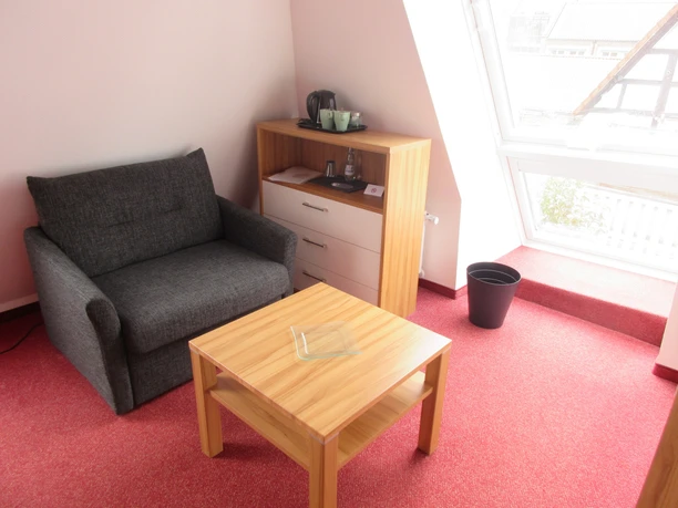 A stylish seating area in a bright room with a red carpet and window.
