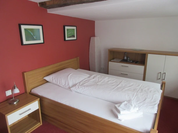 Hotel Ambiente Nienburg Ein helles Einzelzimmer mit Holzdekor, roter Wand und minimalistischer Einrichtung für Gäste.