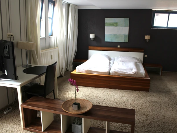 Hotel zum Kanzler Ein modernes Gästezimmer mit Doppelbett, Arbeitsbereich, Tageslicht und stilvollem Dekor lädt ein.