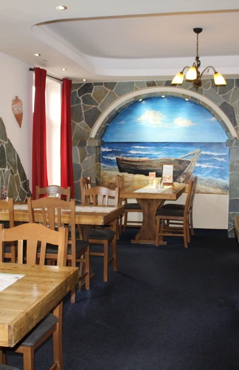 Rustikales Interieur mit Holztischen, roten Vorhängen und Wandgemälde eines Bootes am Strand.Rustic interior with wooden tables, red curtains and a mural of a boat on the beach.Rustikt interiør med træborde, røde gardiner og et vægmaleri af en båd på stranden.Rustiek interieur met houten tafels, rode gordijnen en een muurschildering van een boot op het strand.