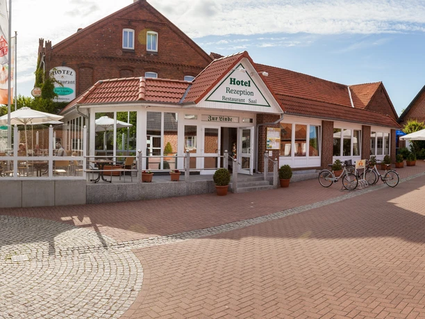 A traditional brick hotel with red tiled roofs, bicycles in front of the entrance and parasols.