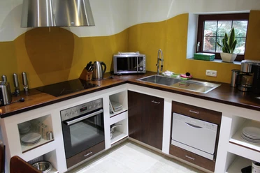 Een moderne keuken met houten werkblad, uitgerust met een fornuis, magnetron en vaatwasser.