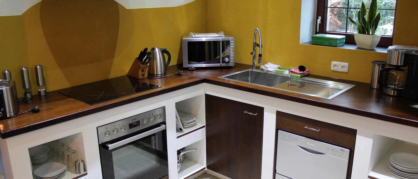 Soulplace Boardinghouse Eine moderne Küche mit Holzarbeitsplatte, ausgestattet mit Herd, Mikrowelle und Spülmaschine.