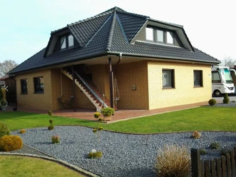Backsteinhaus mit gepflegtem Garten, Außentreppe und überdachter Terrasse in ruhiger Wohnlage