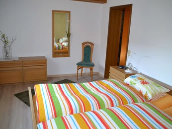 Schlafzimmer mit Doppelbett Stuhl und Spiegel