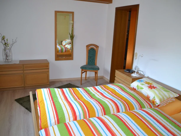 Schlafzimmer mit Doppelbett Stuhl und Spiegel