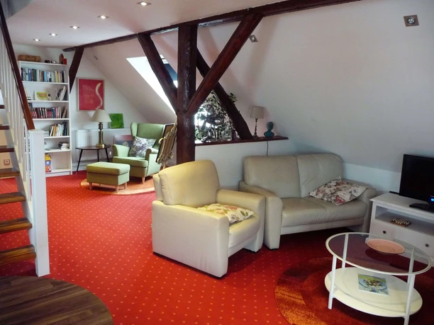 Wohnbereich mit Ledersofa und Lesesessel im Hintergrund