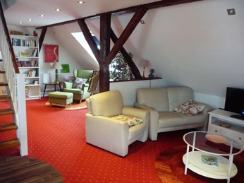 fewo-kuenstlerhauspotthast-spitzboden-wohnbereich Wohnbereich mit Ledersofa und Lesesessel im Hintergrund