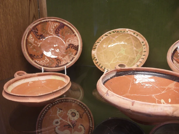 Töpfereimuseum Hagen aTW Ausstellungsstücke Keramikteller mit rötlichem Ton und traditionellen Mustern, ausgestellt im Museum.