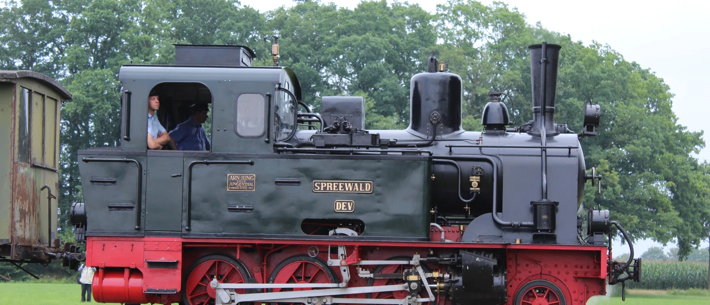 Museums-Eisenbahn Bruchhausen-Vilsen Historic steam locomotive named "Spreewald" on a green meadow with trees in the background, photographed from the side.