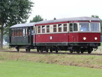 Historischer roter Schienenbus auf grüner Strecke mit Bäumen im Hintergrund bei Museums-Eisenbahn.Historic red rail bus on green track with trees in the background at museum railroad.Historisk rød skinnebus på et grønt spor med træer i baggrunden ved en museumsjernbane.Historische rode railbus op een groen spoor met bomen op de achtergrond bij een museumspoorlijn.