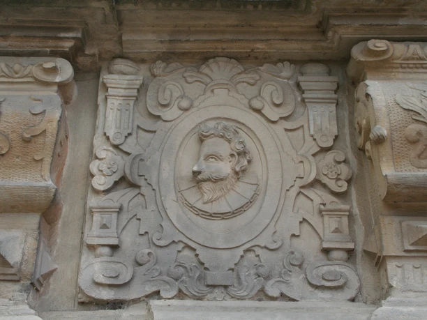 Detail Front Schloss Erbhof Stone relief on a wall with elaborate carvings and a detailed depiction of a portrait of a man.