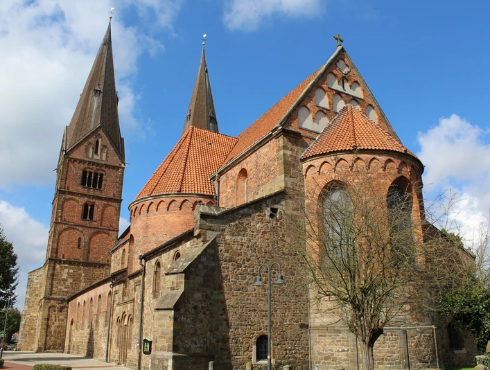 Stiftskirche Bücken Stiftskirche Bücken: Historische Kirche aus rotem Backstein mit markanten Türmen unter blauem Himmel.Bücken collegiate church: Historic red-brick church with striking towers under a blue sky.Den kollegiale kirke i Bücken: Historisk kirke i røde mursten med markante tårne under en blå himmel.Collegiale kerk van Bücken: Historische kerk van rode baksteen met opvallende torens onder een blauwe hemel.