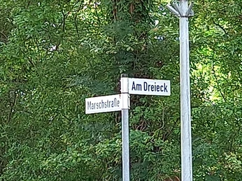 Straßenbeschilderung Rastplatz Marschstrasse Wegweiser an einer Straßenecke mit den Straßennamen "Marschstraße" und "Am Dreieck", umgeben von Bäumen.