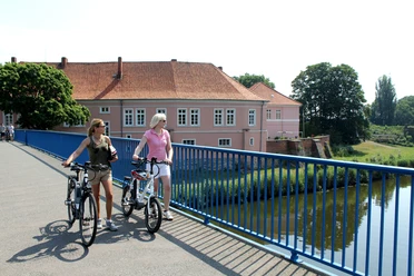 Radfahrer vor dem Grafenschloss in Hoya Zwei Frauen auf Fahrrädern überqueren eine Brücke vor dem historischen Grafenschloss in Hoya.